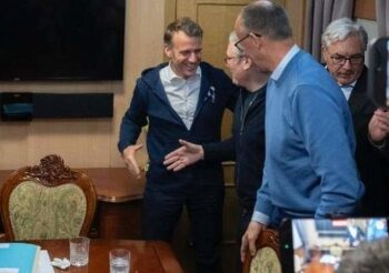 Emmanuel Macron y otros líderes políticos conversando y sonriendo en el interior de un vagón de tren, alrededor de una mesa, en el contexto de su viaje a Kiev.