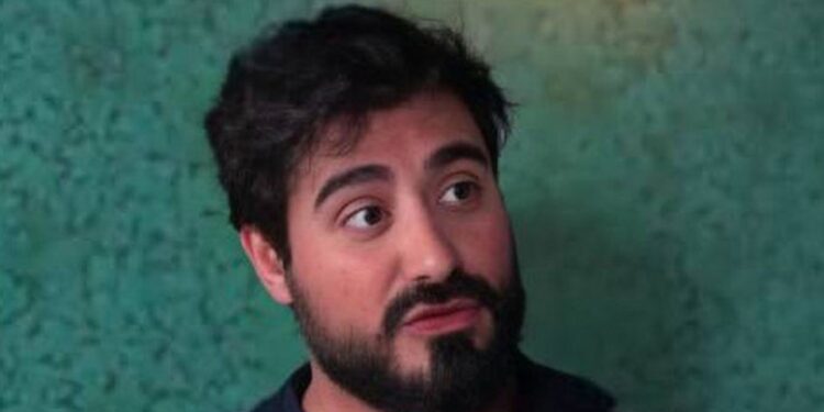 Imagen de Alvise Pérez con gesto serio frente a un fondo verde, en el contexto de la apertura de diligencias previas por parte del Tribunal Supremo por presunta financiación ilegal.