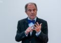 El doctor Alfonso López Borgoñoz durante una charla, gesticulando mientras argumenta a favor del uso del dinero en efectivo, en el contexto de su defensa de las libertades individuales y la privacidad financiera.