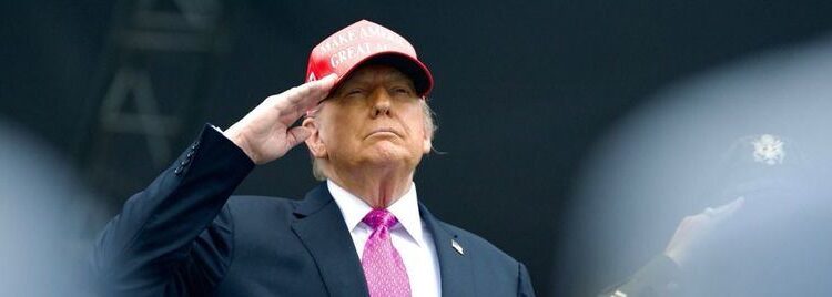 Donald Trump saluda militarmente con una gorra roja de "Make America Great Again", durante un acto público, en el contexto de sus declaraciones sobre un nuevo acuerdo comercial con Europa.
